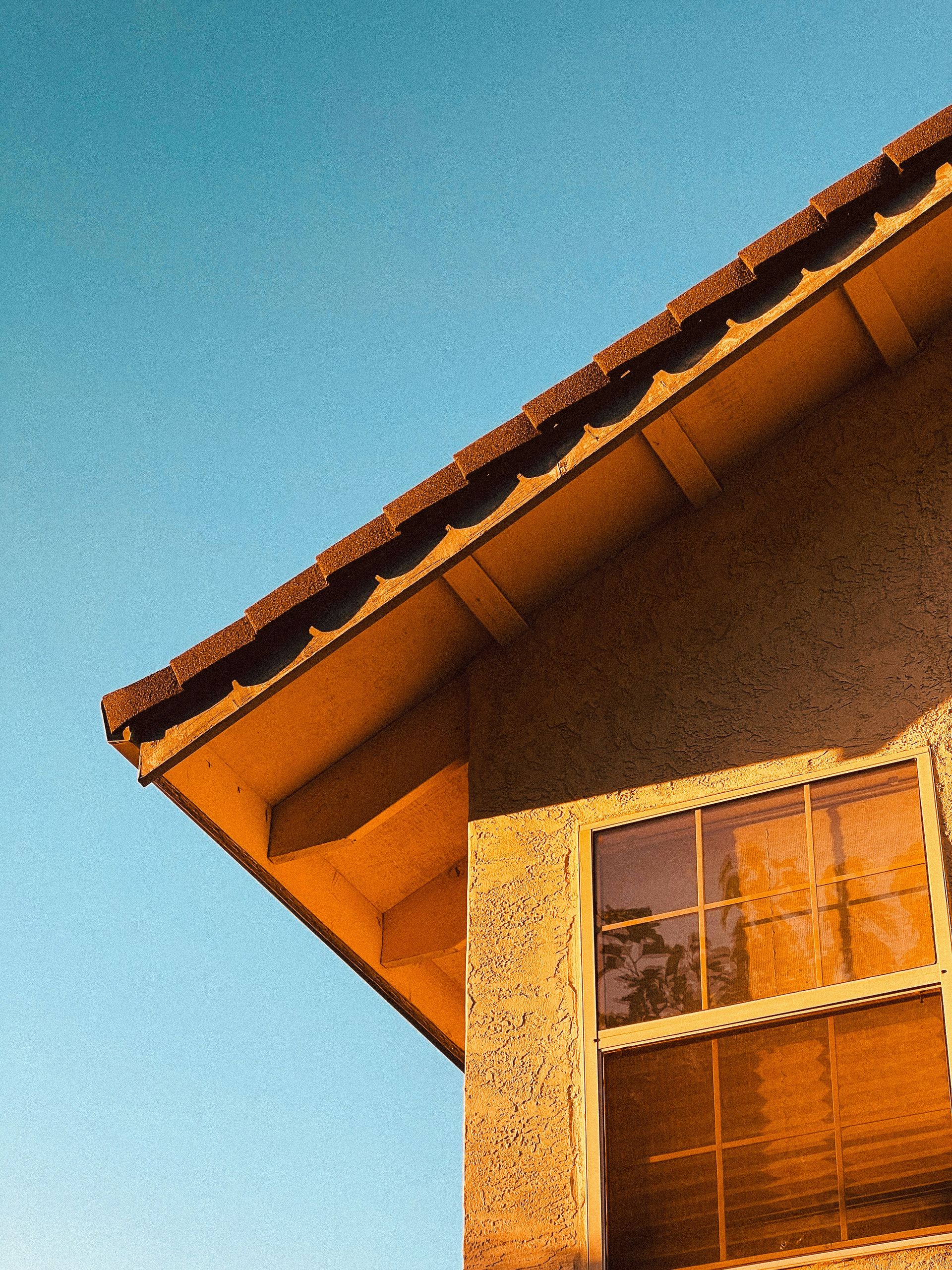 Corner of a house with a window against blue sky